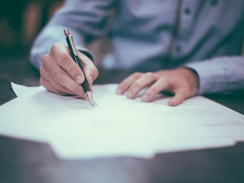 A fountain pen poised over a confidential settlement document