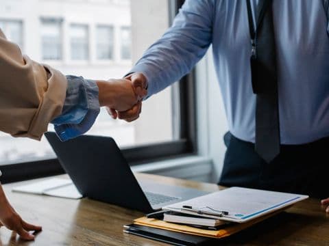 A handshake over the table — terms agreed before proceedings are issued